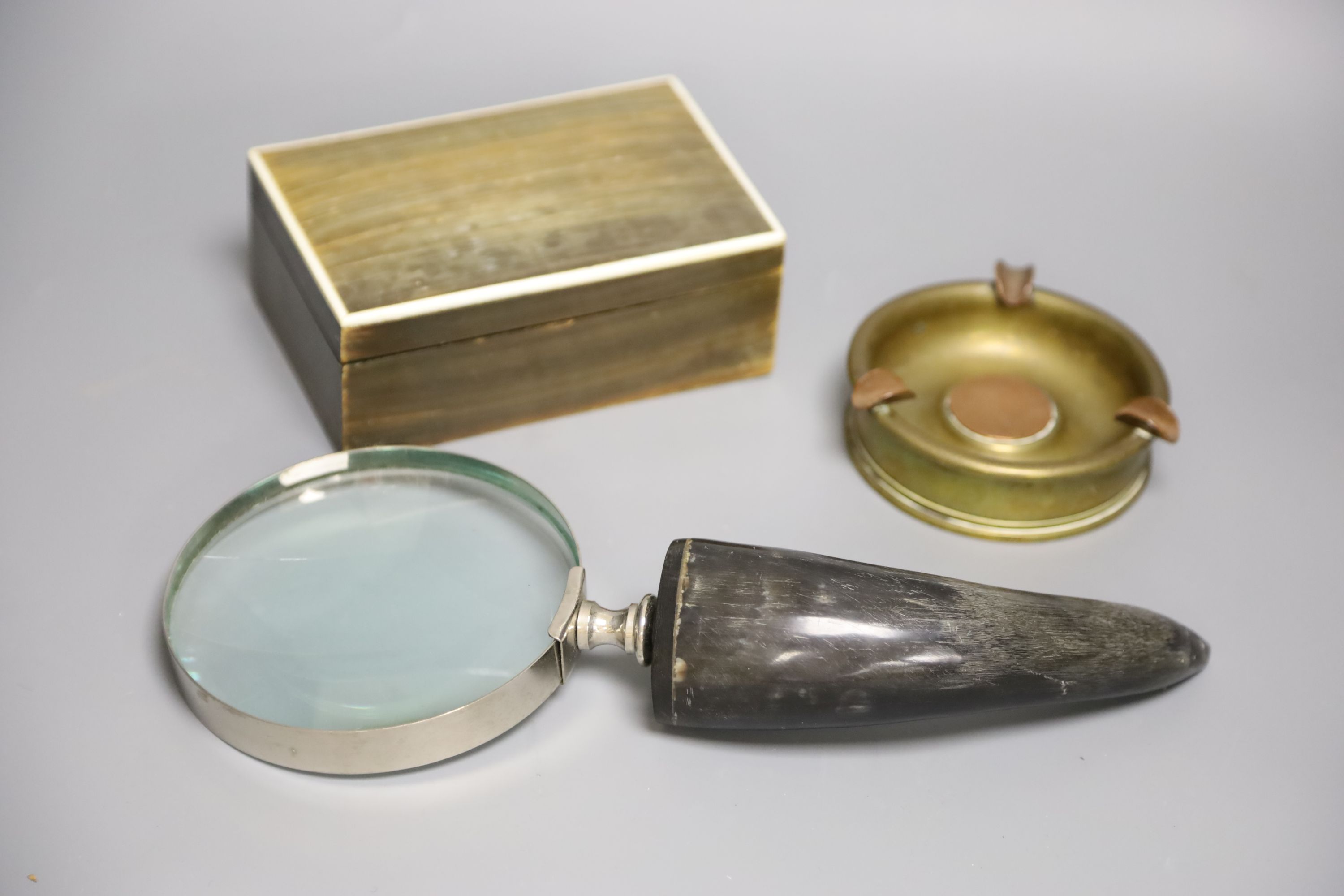 A horn veneered cigarette box, a horn handled magnifying glass and a Trench art ashtray